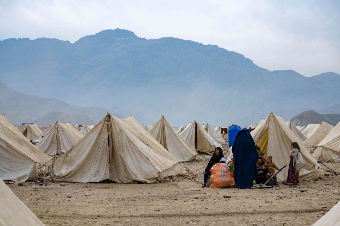 Frauen und Mädchen vor einem Zelt auf steinigem Boden, rundherum stehen noch viele andere Zelte.